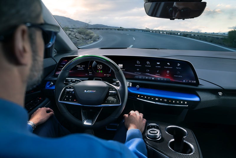 Front View of the 2026 OPTIQ-V Driving Through the Dusk Utilizing its Headlights | Dellenbach Cadillac in FORT COLLINS CO