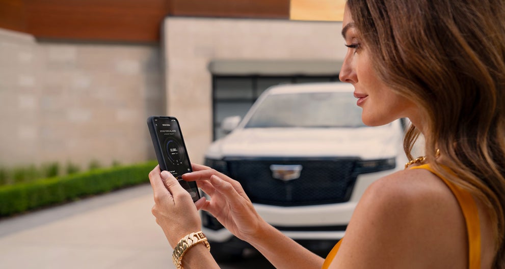lady checking her mobile with a Cadillac vehicle background | Dellenbach Cadillac in FORT COLLINS CO